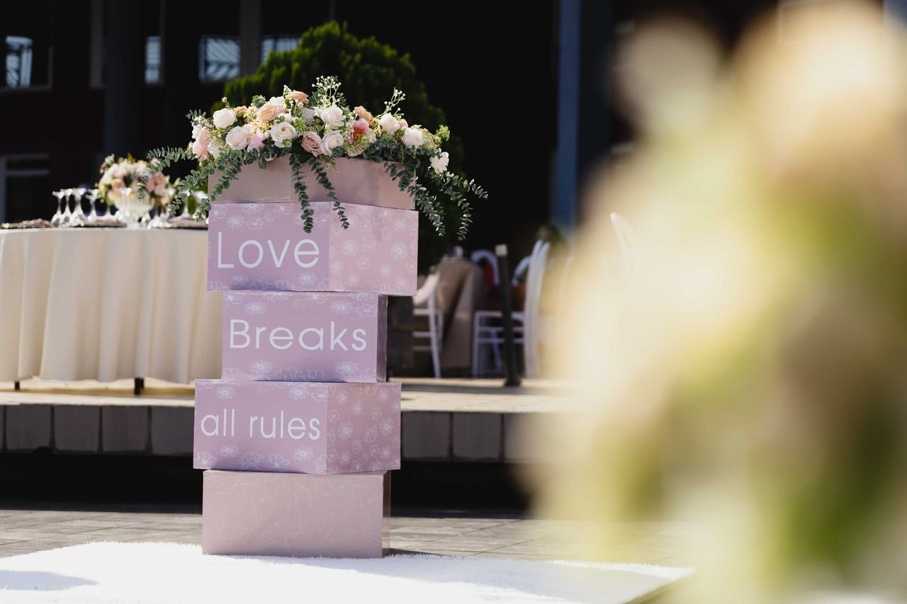 ours-journey Outdoor wedding setting with floral decorations and "Love Breaks all rules" signage.
