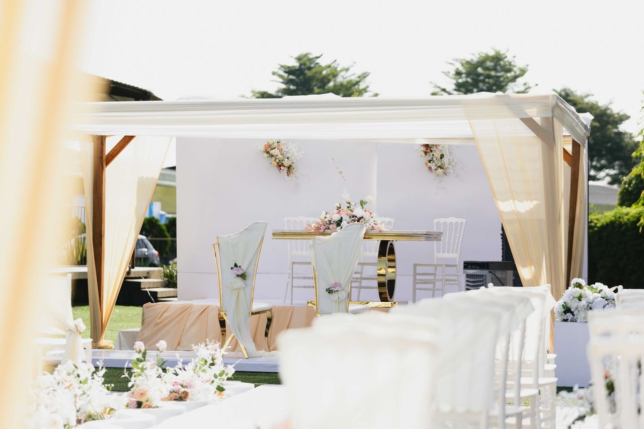 our-experience Beautiful outdoor wedding ceremony setting with white and pastel-colored decor and floral arrangements.